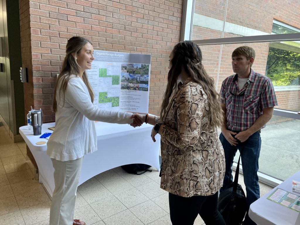 Callie Bowling, intern, greets a visitor to her display about her work during her internship with UT Extension as Andrew Griffith, professor, observes.